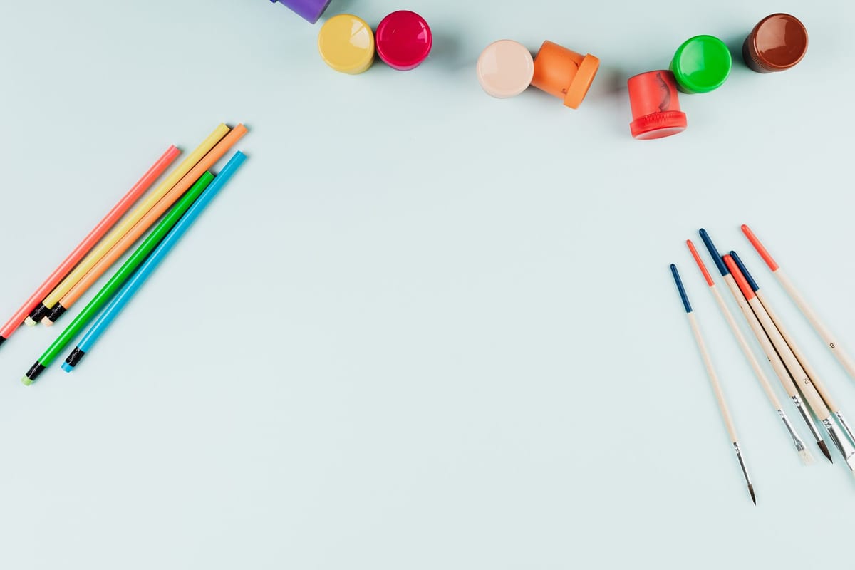 A creative craft table with art supplies, paint brushes and yarn